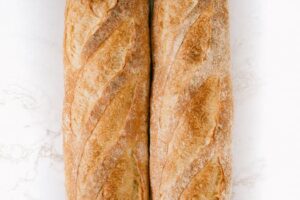 Freshly baked baguettes on a marble surface, showcasing rustic texture and golden crust.
